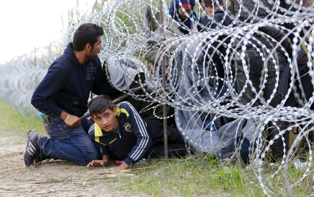 Migranti prekračujú plot v Maďarsku. Snímka: Reuter