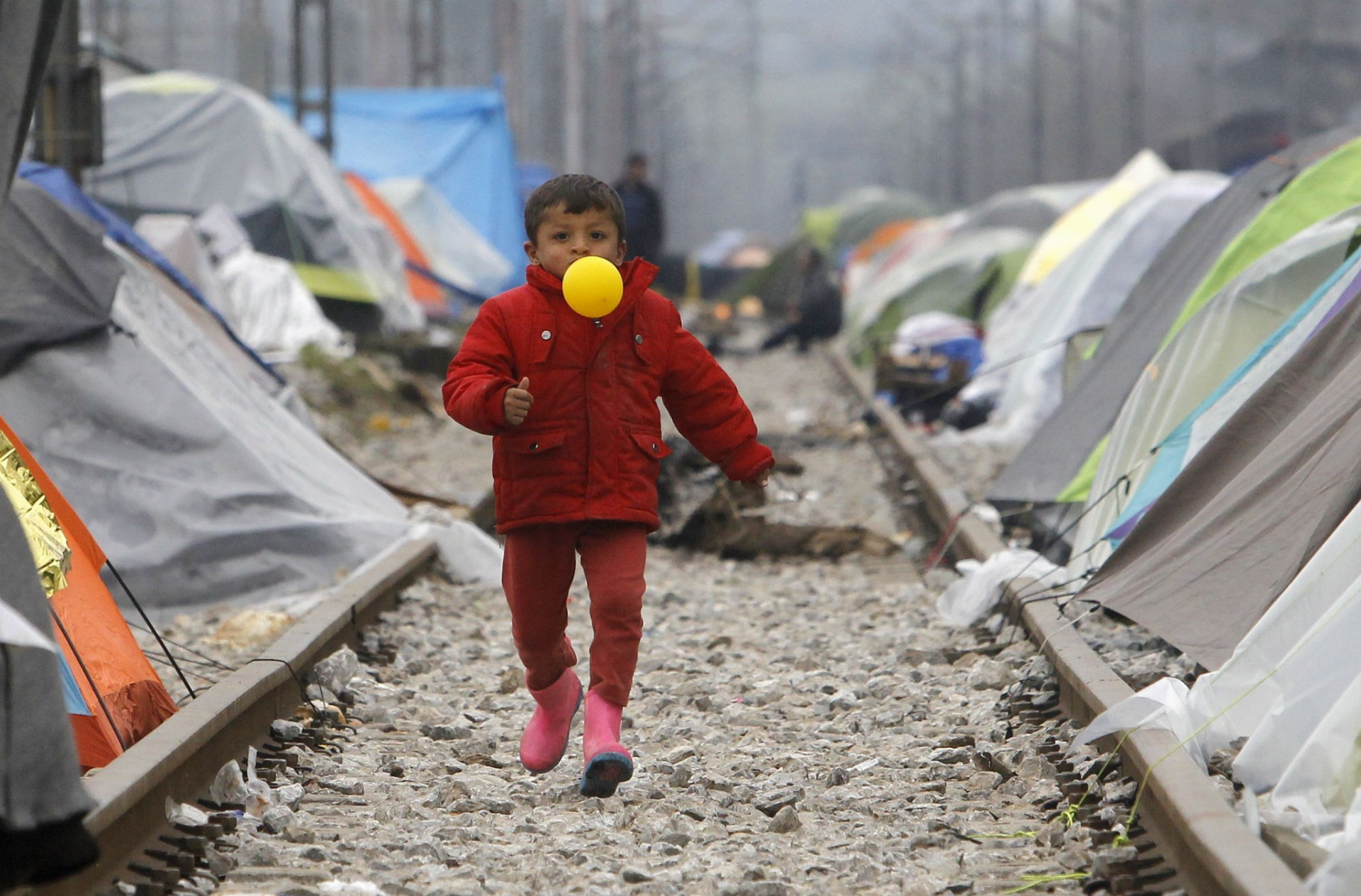 Chlapček z utečeneckého tábora Idomeni sa hrá s balónom.