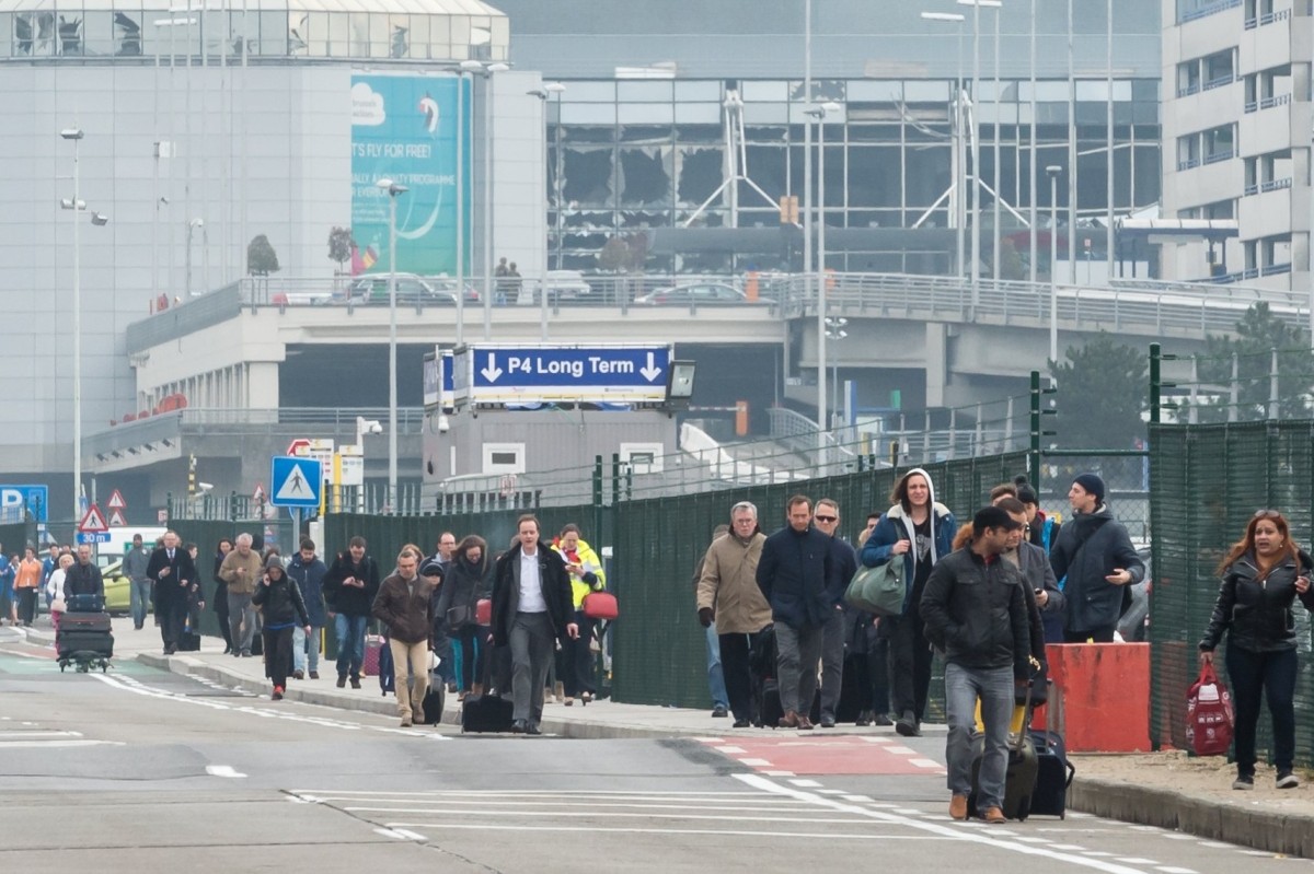 Ľudia opúšťajú bruselské letisko po teroristických útokoch.