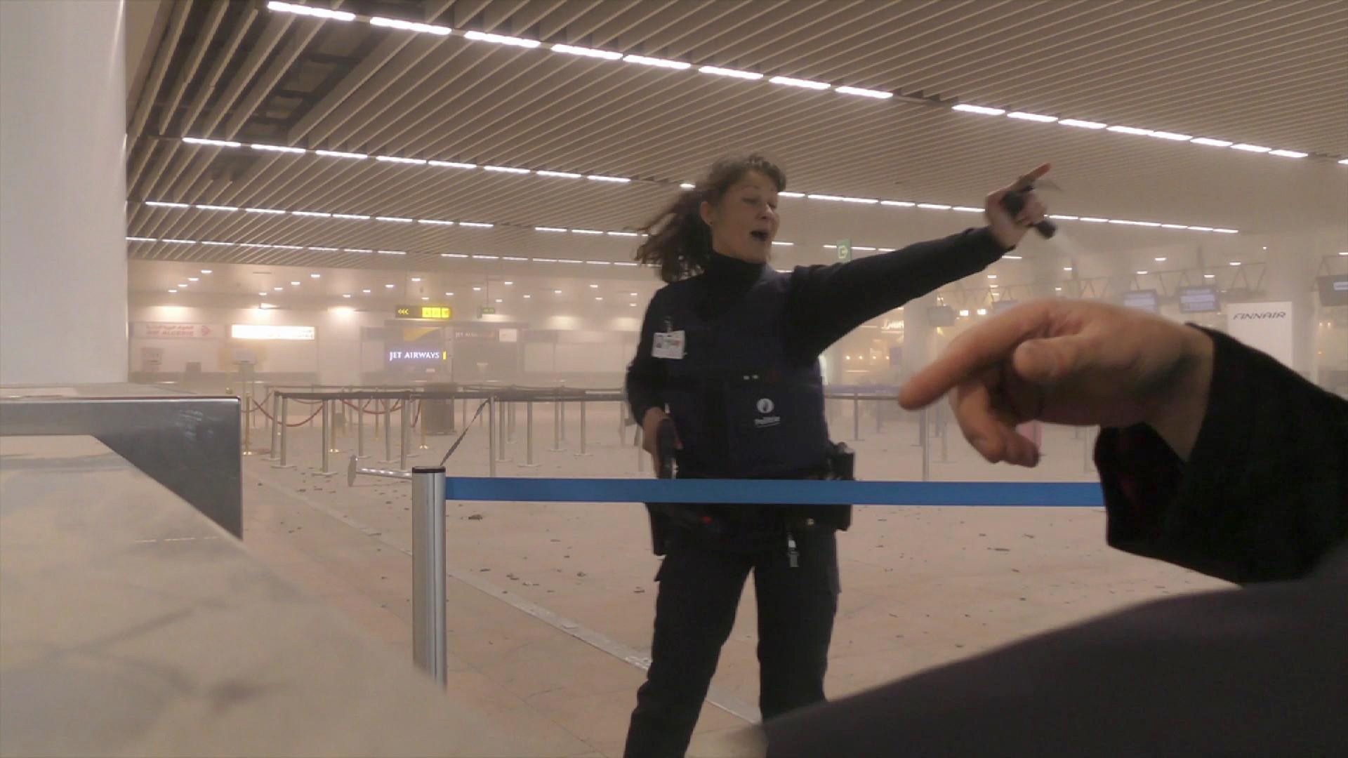 Policajtka na bruselskom letisku usmerňuje ľudí po útoku teroristov