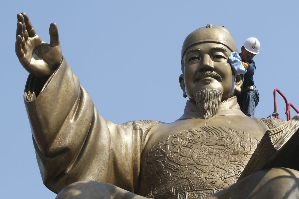 Zamestnanci čistia veľkú bronzovú sochu kórejského kráľa Sedžonga v Soule.