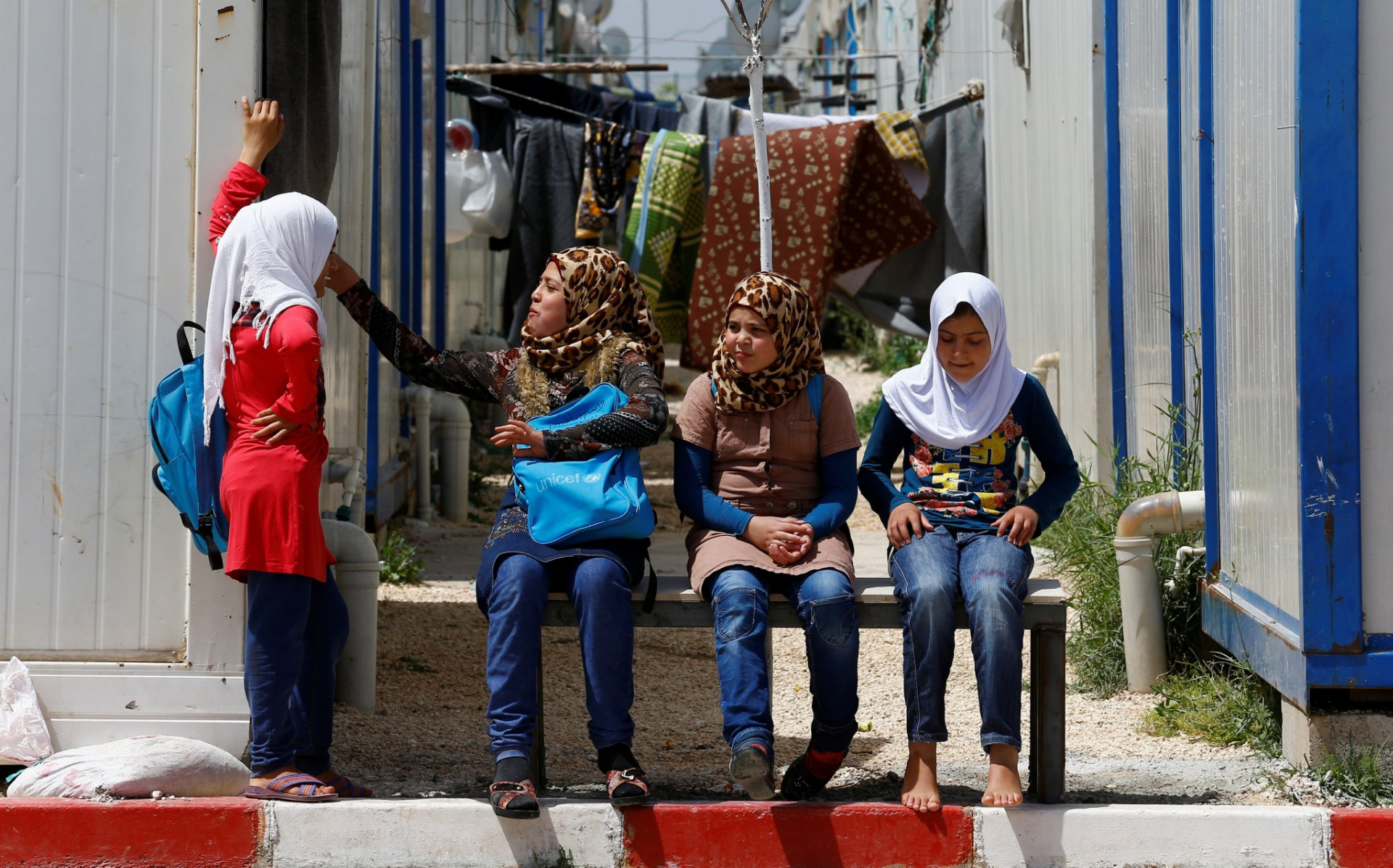 Sýrske dievčatá sedia pri kontajneroch, v ktorých sú ubytované, v utečeneckom tábore.