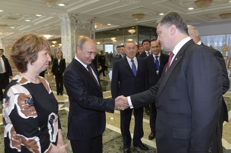 Ukrajinský prezident Petro Porošenko si vedľa Catherine Ashtonovej podáva ruku s Vladimirom Putinom.