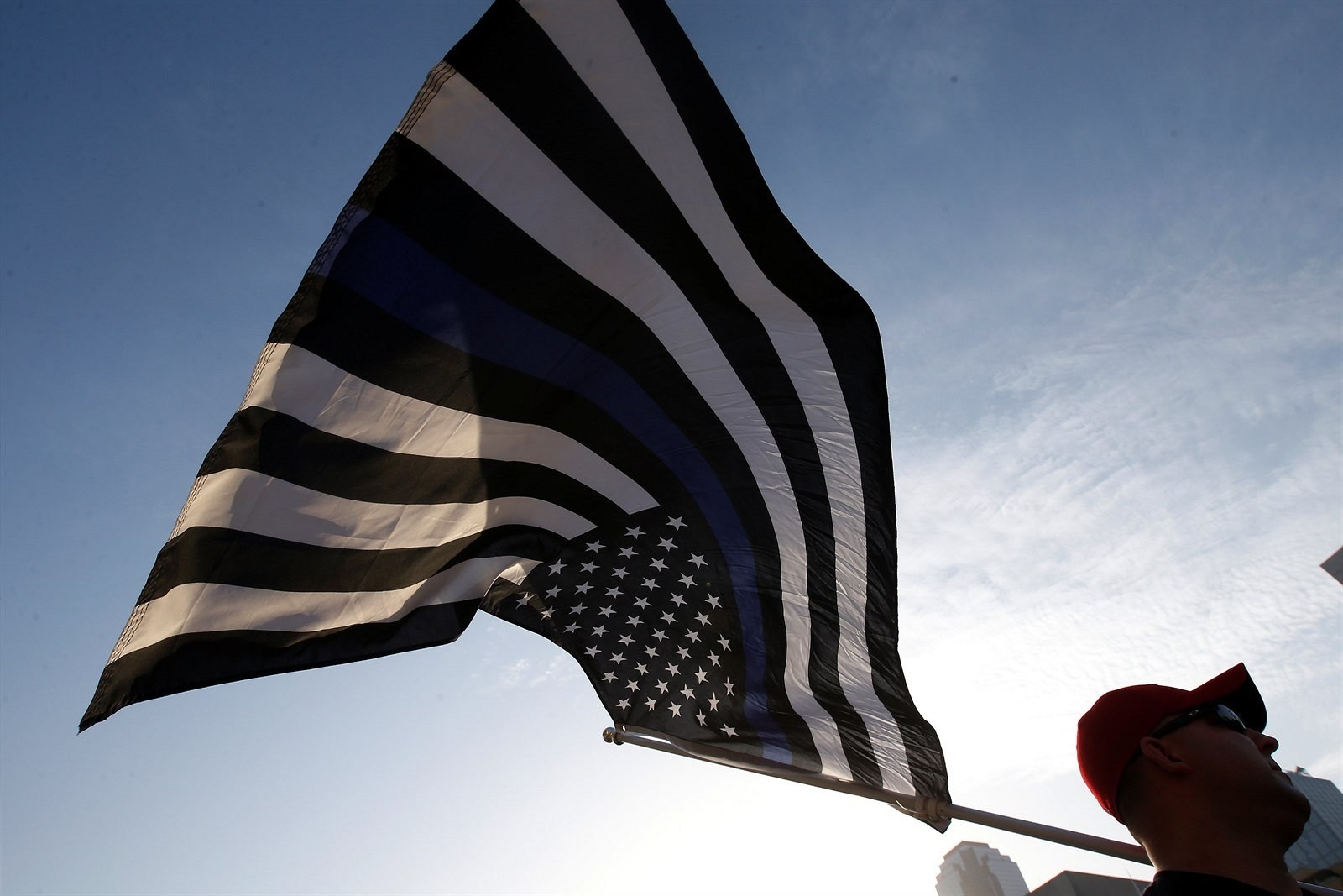 Na spomienkovom obrade v Dallase sa objavila takáto čiernobiela americká vlajka s modrým pruhom. Ten symbolizuje políciu, ktorá stojí medzi spoločnosťou a zločincami. 