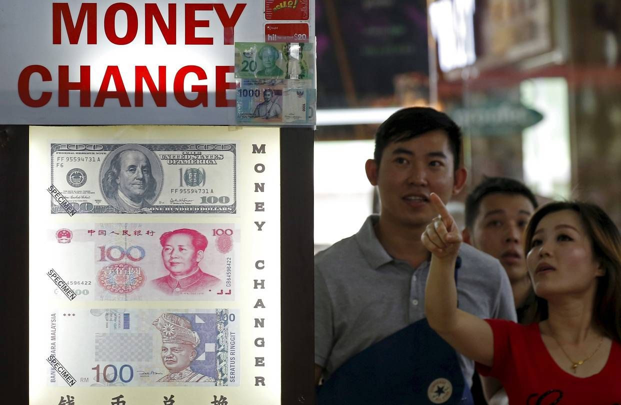 Čína roky hromadila devízové rezervy, teraz potrebuje prehĺbiť domáci finančný systém. Na ilustračnej snímke Číňania pozerajú na tabuľu s výmenným kurzom amerického dolára, čínskeho renminbi a malajzijského ringgitu.