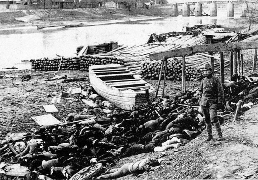 Japonský vojak na brehu rieky pri telách obetí nankinského masakru.