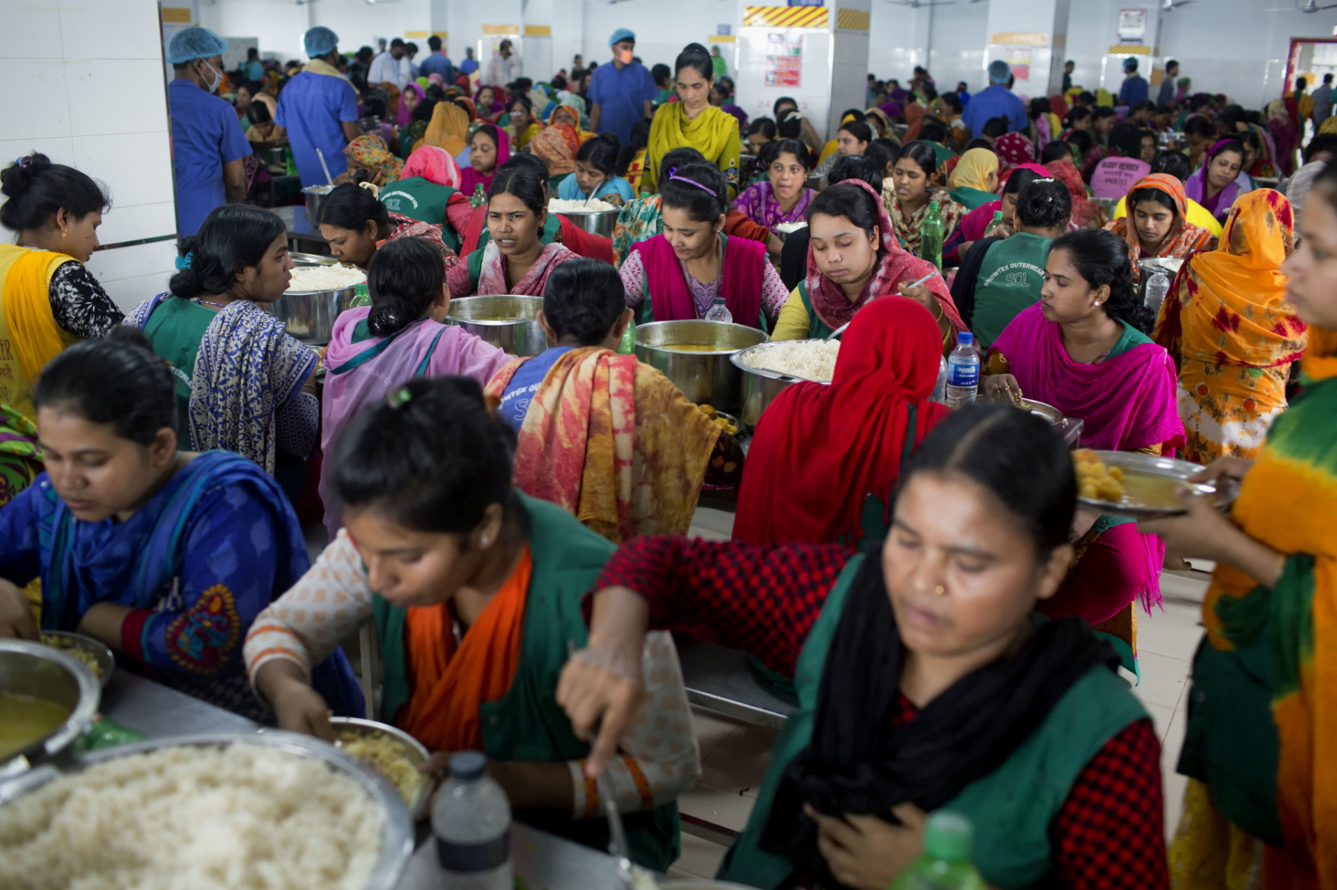 Transfer priemyselných odvetví do oblastí s nízkymi platmi prispieva k stagnácii životnej úrovne strednej vrstvy. Na snímke sú pracovníčky textilky v Bangladéši počas obeda.