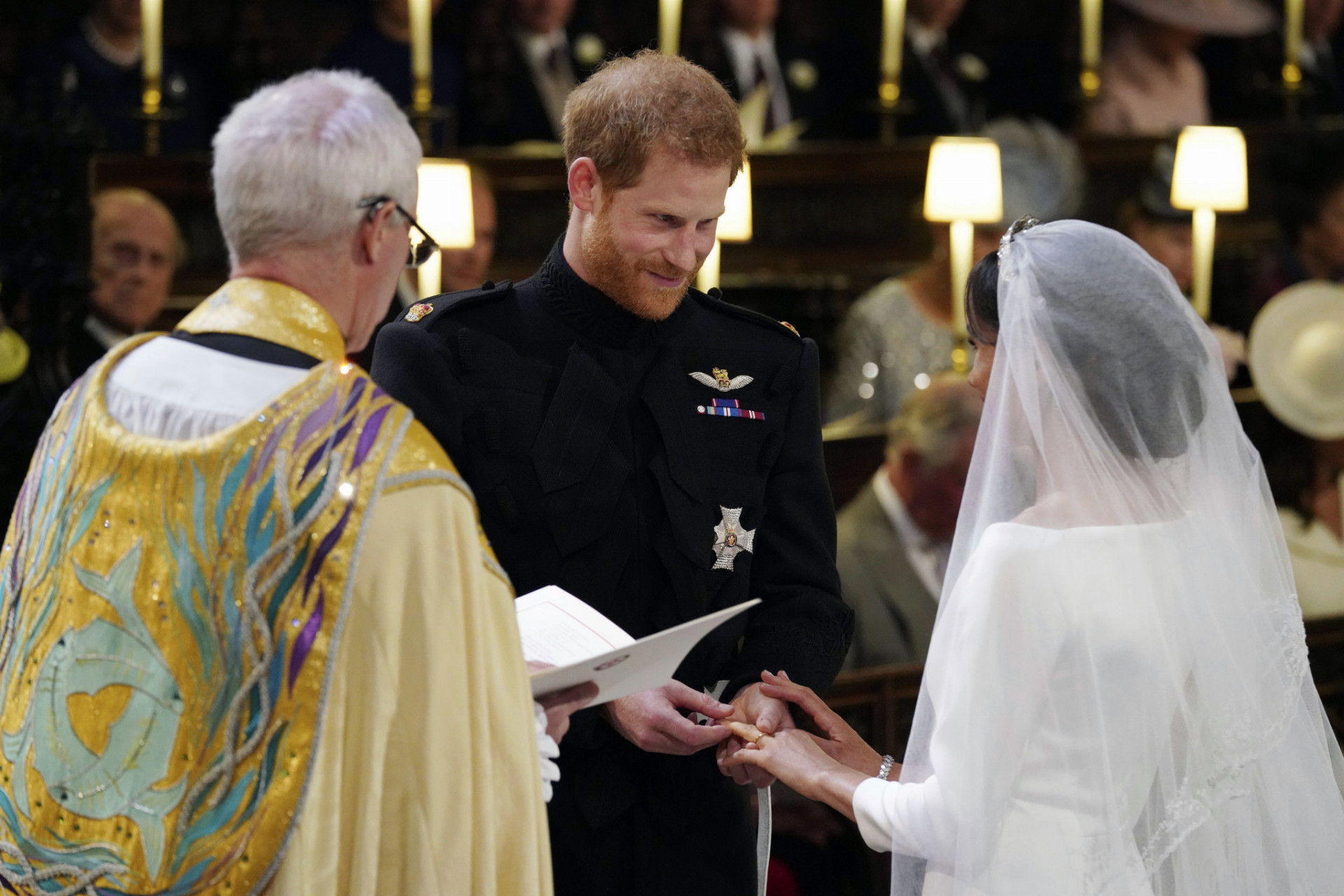 Na snímke uprostred ženích britský princ Harry navlieka obrúčku neveste Meghan Markleovej (vpravo), vľavo arcibiskup z Canterbury Justin Welby počas sobášneho ceremoniálu v Kaplnke sv. Juraja na kráľovskom zámku vo Windsore v sobotu 19. mája 2018.