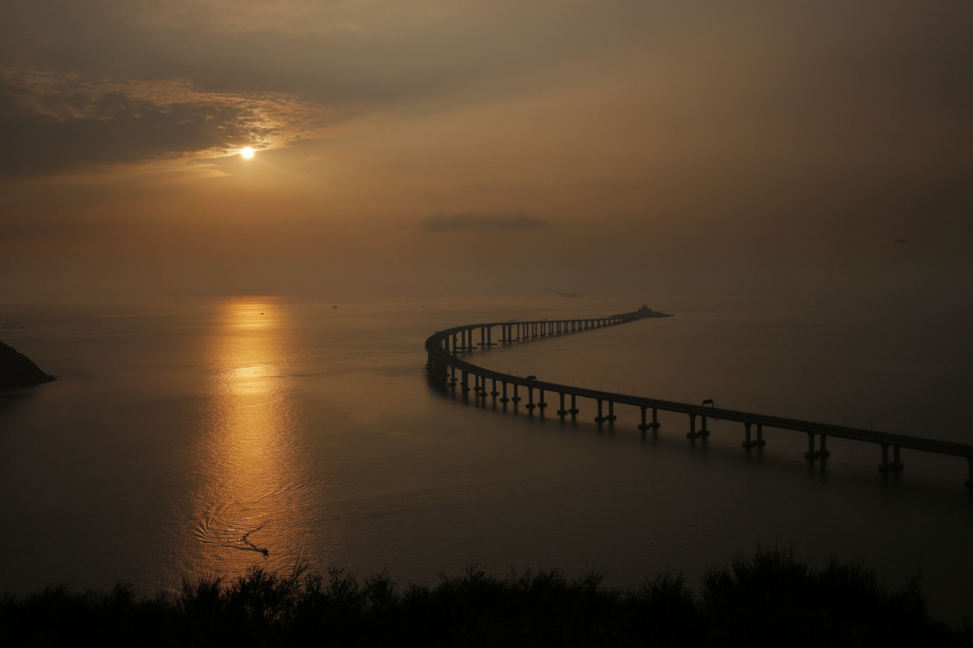 Na snímke západ slnka nad najdlhším mostom na svete, 55 kilometrov dlhou komunikáciou, ktorá spája Hongkong, Macao a čínske pevninské mesto Ču-chaj v Honkongu 22. októbra 2018.
