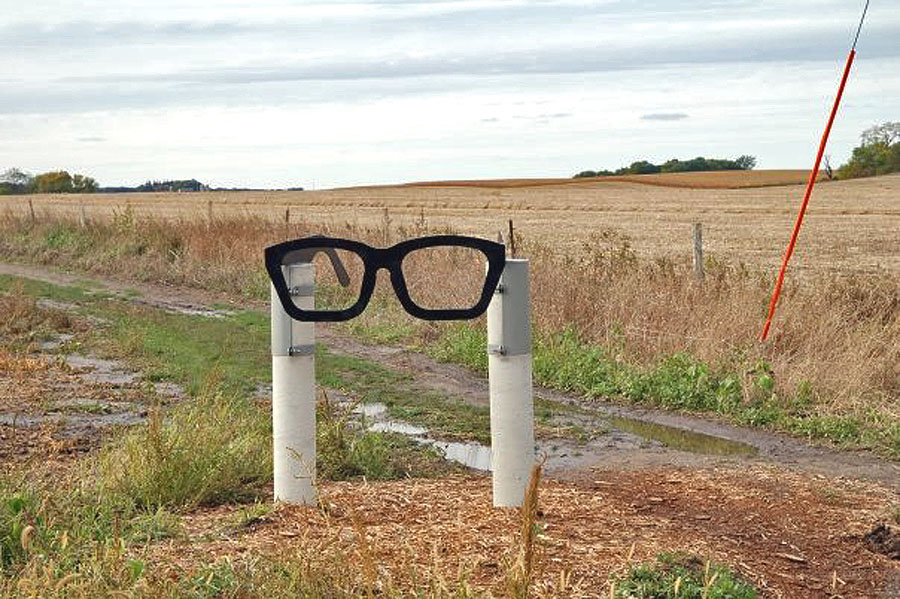 K pamätníku nešťastia ľudí navádza smerovka v podobe typických okuliarov, aké Buddy Holly nosil.