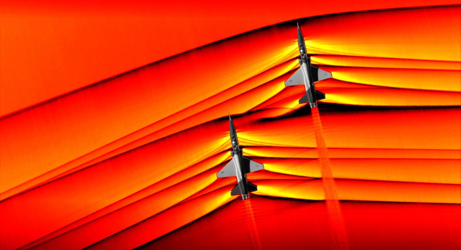 Zachytáva moment, keď sa stretávajú tlakové vlny dvoch lietadiel spôsobené prelomením zvukovej bariéry.