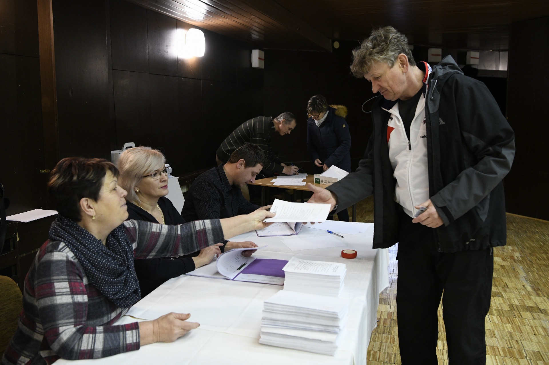 Na snímke volič si od členov okrskovej volebnej komisie preberá hlasovacie lístky počas 1. kola prezidentských volieb, 16. marca 2019 v Ilave.