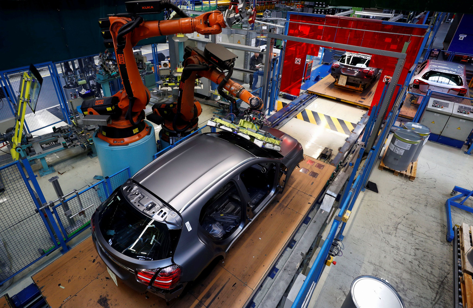 Robot inštaluje čelné sklo na vozidlo Mercedes. Automobilky očakávajú, že na výrobu elektrických áut budú potrebovať menej zamestnancov.