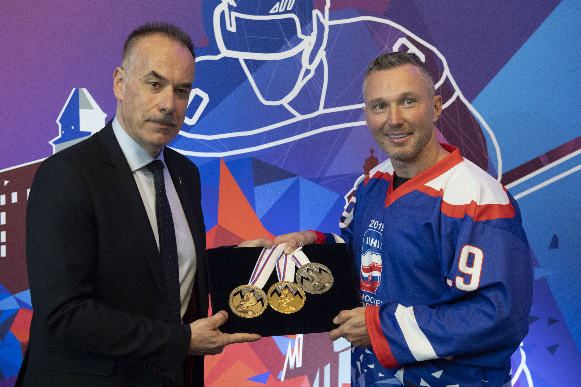 Igor Nemeček (vľavo) a Ľubomír Višňovský pózujú s medailami pre víťazné tímy hokejového šampionátu 2019.