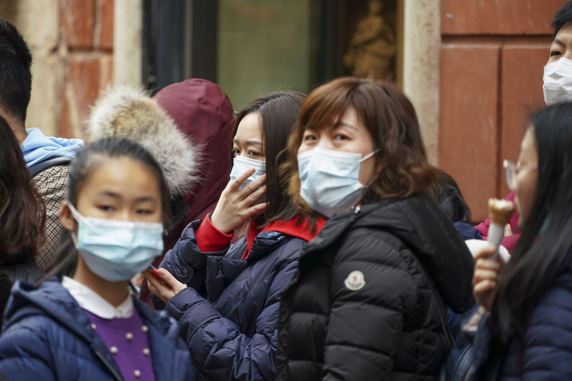 Čínski turisti s ochrannými rúškami na tvári kráčajú po ulici v Ríme