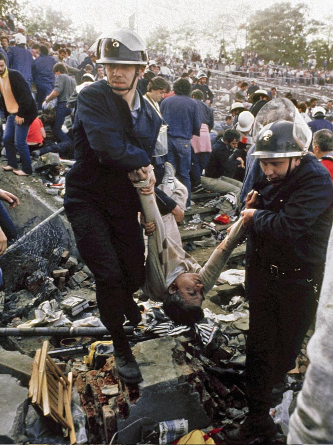 Policajti odnášajú telá obetí, väčšinou fanúšikov Juventusu Turín, ktorí prišli o život pri násilnostiach pred finále PEM v máji 1985 na štadióne Heysel v Bruseli. Tragédia si napokon vyžiadala 39 mŕtvych a asi 600 zranených.