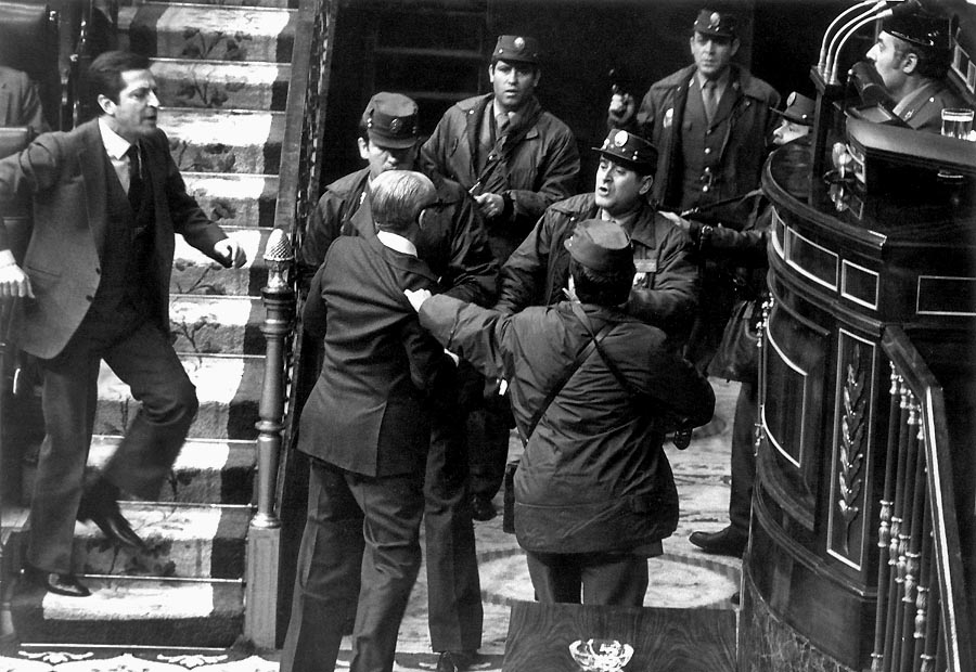 Manuel Gutiérrez Mellado (v civile, otočený chrbtom) počas potýčky s ozbrojencami 23. februára 1981 v španielskom parlamente. Celkom vľavo je premiér Adolfo Suaréz, ktorý mu prichádza na pomoc. Oboch, a spolu s nimi ešte ďalších štyroch politikov, ktorí kládli odpor, vzbúrenci napokon zo sály odviedli a izolovali ich od ostatných.