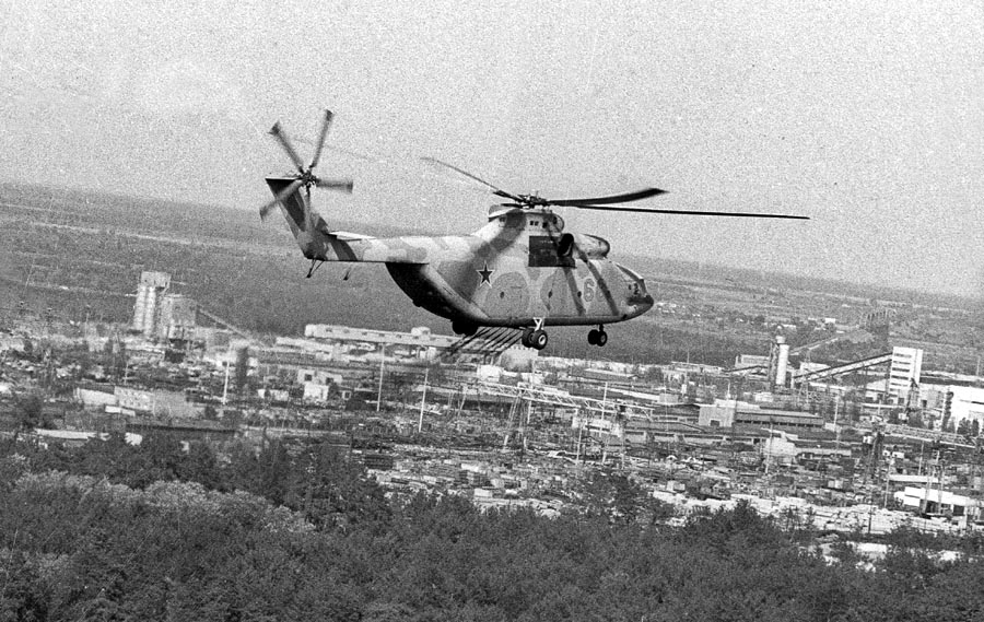Archívna fotografia z 12. mája 1986 zachytáva vrtuľník, ktorý rozprašuje chemikálie určené na elimináciu radiácie zo zničeného reaktora jadrovej elektrárne Černobyľ. 