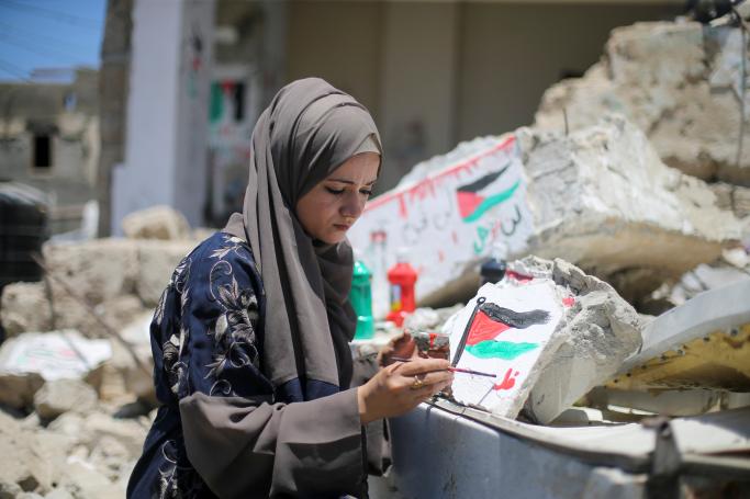 Mladá palestínska umelkyňa Saja Mousa maľuje na zvyšky svojho domu zničené pri izraelských leteckých útokoch na pásmo Gazy počas vyostrenia izraelsko-palestínskeho konfliktu v máji tohto roku.