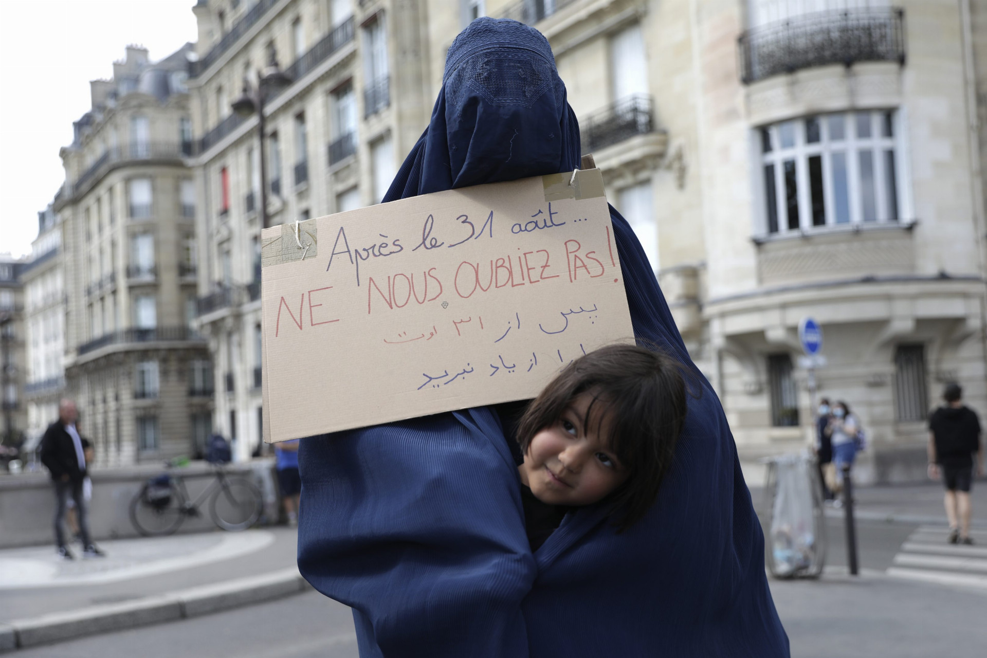 Žena v burke drží transparent s nápisom Nezabudnite na nás po 31. auguste na zhromaždení, na ktorom prítomní vyjadrili solidaritu s afganskými ženami v Paríži v sobotu 28. augusta 2021.