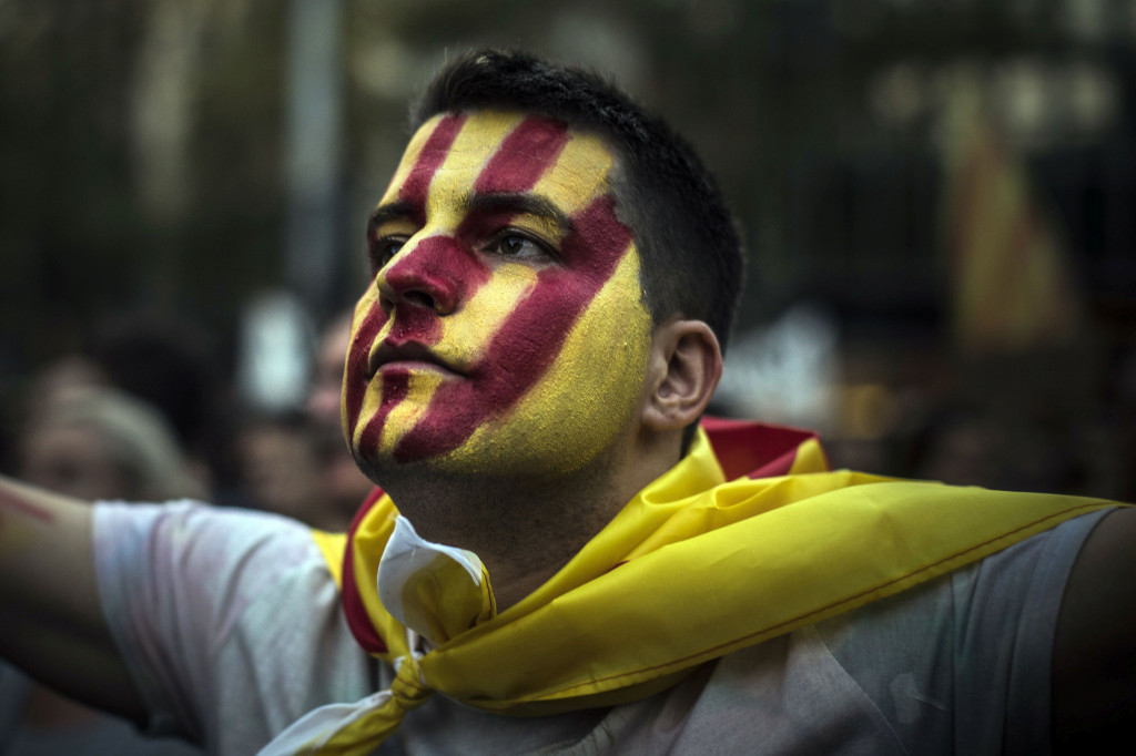 Demonštrant s tvárou pomaľovanou vo farbách katalánskej zástavy počas protestného zhromaždenia v Barcelone 