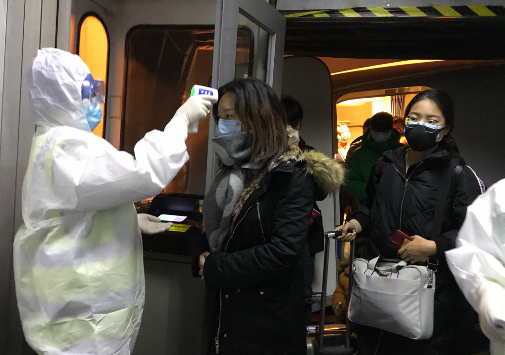 Zdravotníci v Pekingu merajú telesnú teplotu cestujúcim, ktorí pricestovali z Wu-chanu.