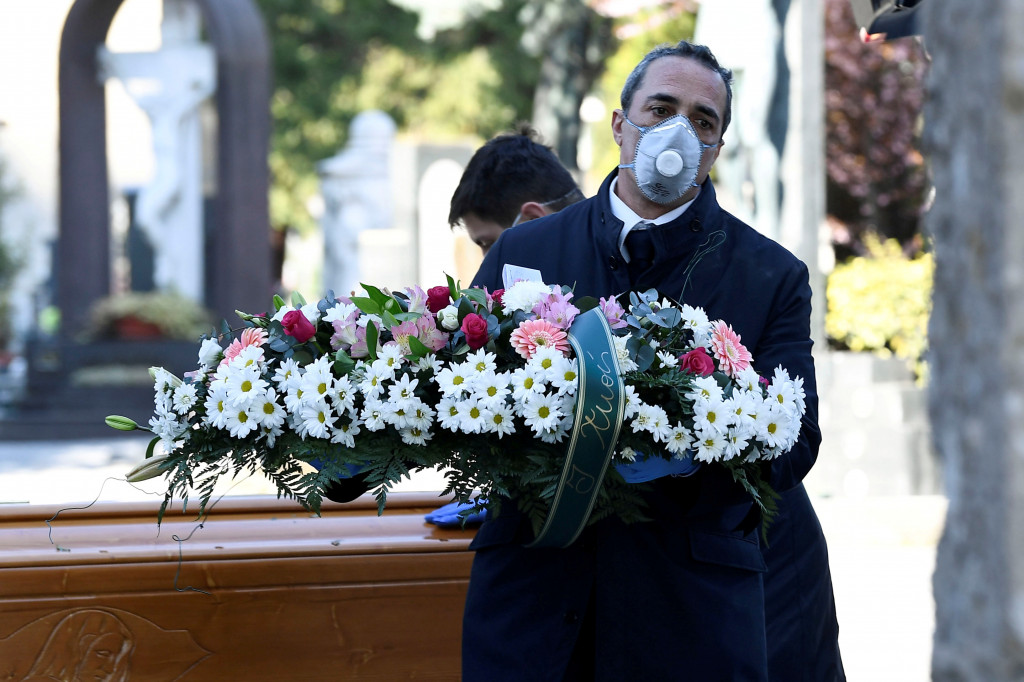 Pracovník pohrebnej služby v Taliansku sa chráni rúškom pred koronavírusom