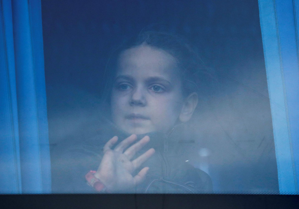 Dievčatko pozerajúce sa z okna autobusu počas evakuácie civilistov z oceliarní Azovstaľ v Mariupole. FOTO: REUTERS