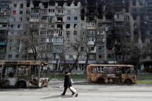 Miestny obyvateľ kráča po ulici okolo vyhorených autobusov v prístavnom meste Mariupol. FOTO: REUTERS