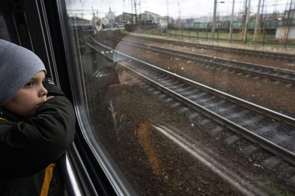 Serhij sa pozerá z okna vlaku pred príchodom do Ľvova s rodinou. FOTO TASR/AP

