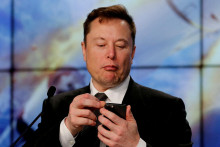 Elon Musk pozerá na svoj telefón. FOTO: REUTERS/Joe Skipper