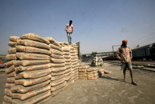 Pracovníci stoja pri vreciach cementu. FOTO: Reuters