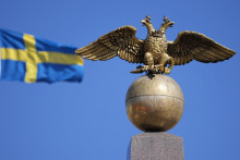 Švédska vlajka veje pri zlatom dvojhlavom orlovi, štátnom znaku Ruska na námestí v Helsinkách. FOTO: TASR/AP
