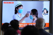 Cestujúci v KĽDR sledujú na televíznej obrazovke správy o výskyte ochorenia.