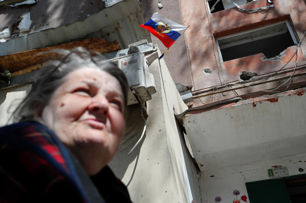 &lt;p&gt;Žena kráča pozdĺž zničenej budovy v Mariupole, v ktorej ruinách je zapichnutá ruská vlajka. FOTO: Reuters&lt;/p&gt;