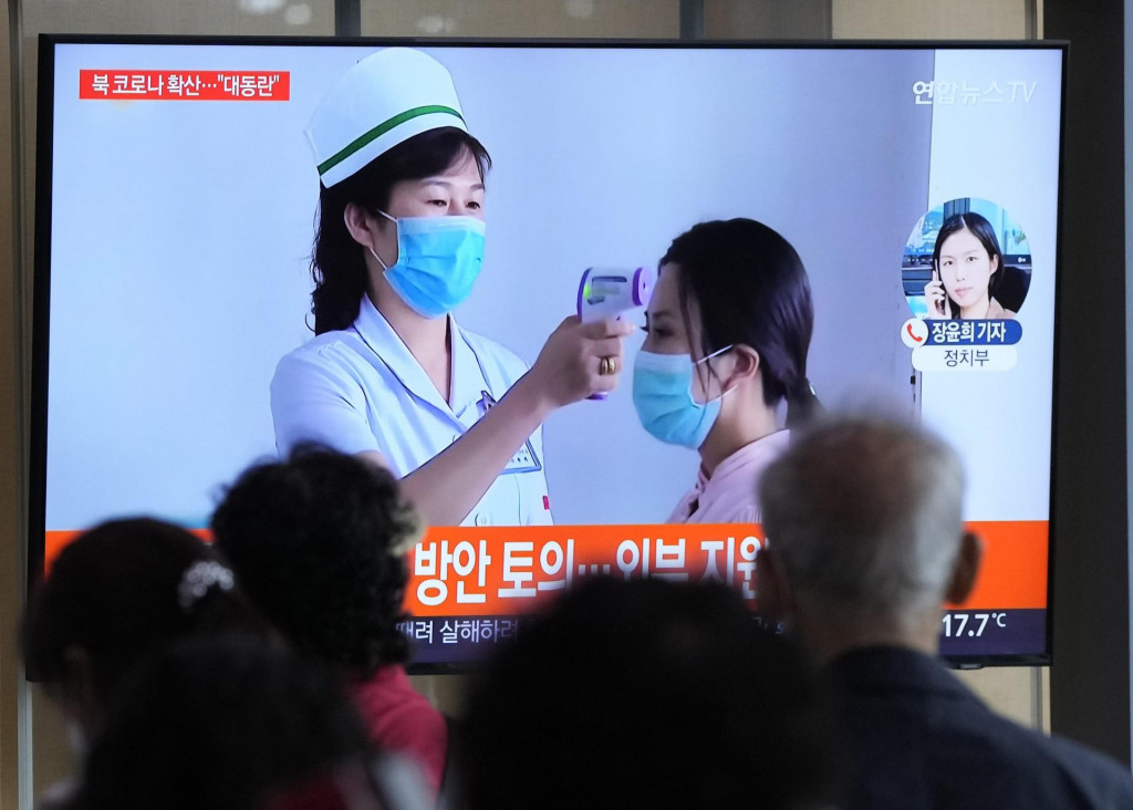 Cestujúci v KĽDR sledujú na televíznej obrazovke správy o výskyte ochorenia.