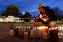 Muž páli sviečku pri pamätníku obetiam na mieste streľby v supermarkete Tops v Buffale, New York, USA, 16. mája 2022. REUTERS/Brendan McDermid