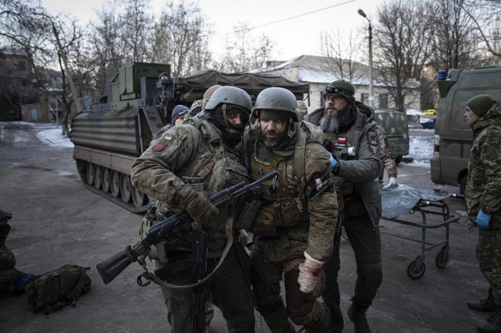 Ukrajinský vojak pomáha svojmu zranenému kolegovi prejsť do nemocnice v Doneckej oblasti na východe Ukrajiny v pondelok 9. januára 2023. FOTO: TASR/AP