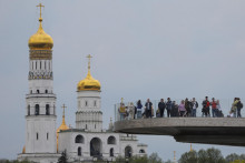 Ľudia si užívajú výhľady z mosta pre peších v parku Zaryadye, s vežou Ivana Veľkého v pozadí, v Moskve, Rusko. FOTO: Reuters