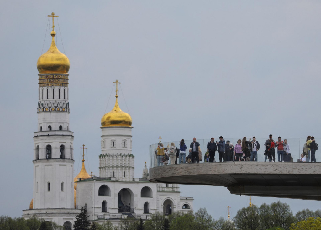 Ľudia si užívajú výhľady z mosta pre peších v parku Zaryadye, s vežou Ivana Veľkého v pozadí, v Moskve, Rusko. FOTO: Reuters