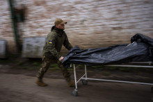 Americký dobrovoľník Darrell Loveless preváža mŕtve telá z chladiarenských vozidiel do márnice v meste Buča v Kyjevskej oblasti. FOTO: TASR/AP

