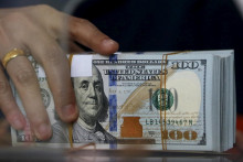 Zamestnanec zmenárne drží v rukách dolárové bankovky. FOTO: REUTERS
