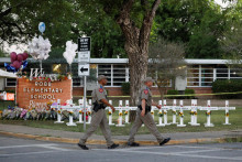 Príslušníci texaského ministerstva verejnej bezpečnosti prechádzajú okolo pamätníka pred základnou školou, kde strelec zabil 19 detí a dvoch učiteľov v Texase. FOTO: REUTERS