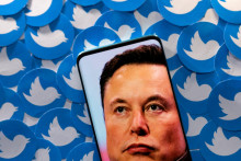 Elon Musk na obrazovke telefónu, v pozadí logo Twitteru. FOTO: Reuters