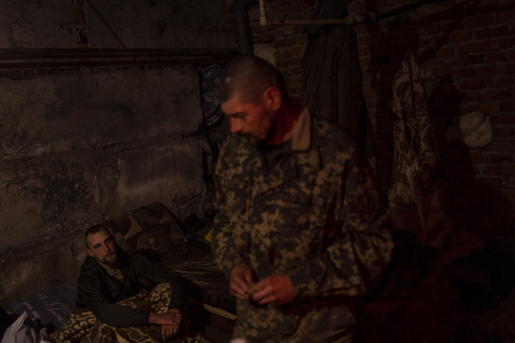 Príslušníci územnej obrany ukrajinskej armády sa zhromažďujú v pivnici počas prestávky po návrate z frontu v Charkovskej oblasti. FOTO: TASR/AP
