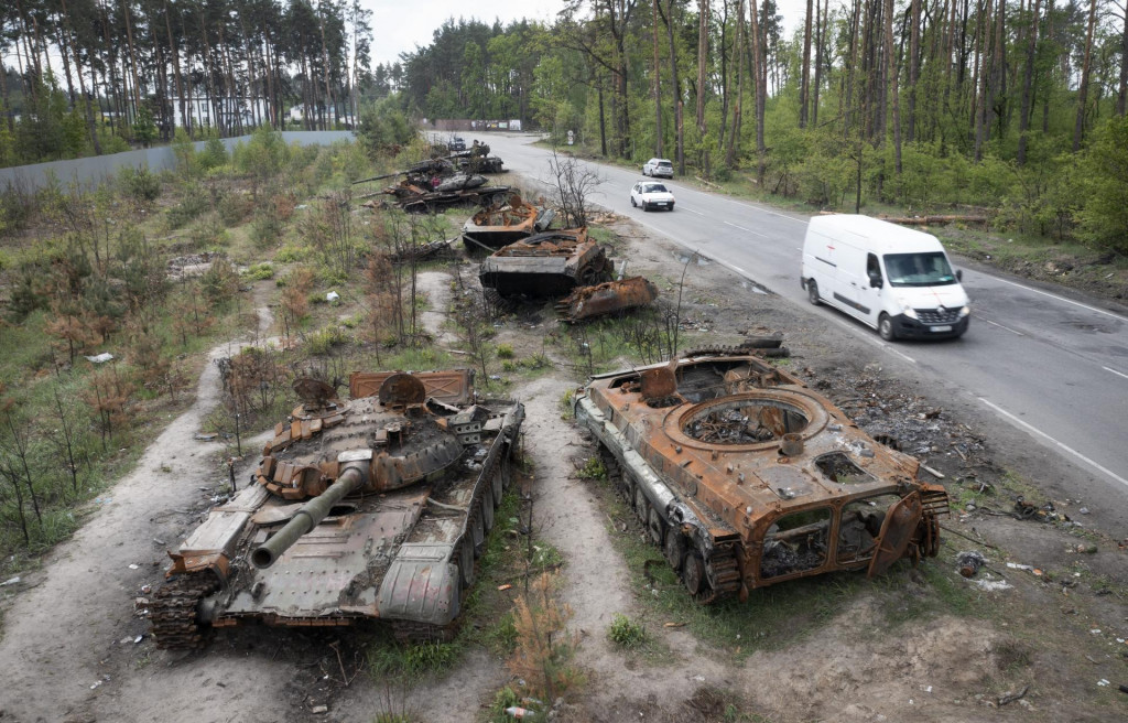 Vozidlá jazdia okolo zničených ruských tankov v dedine Dmytrivka pri Kyjeve počas ruskej invázie na Ukrajinu, 23. mája 2022. FOTO: TASR/AP