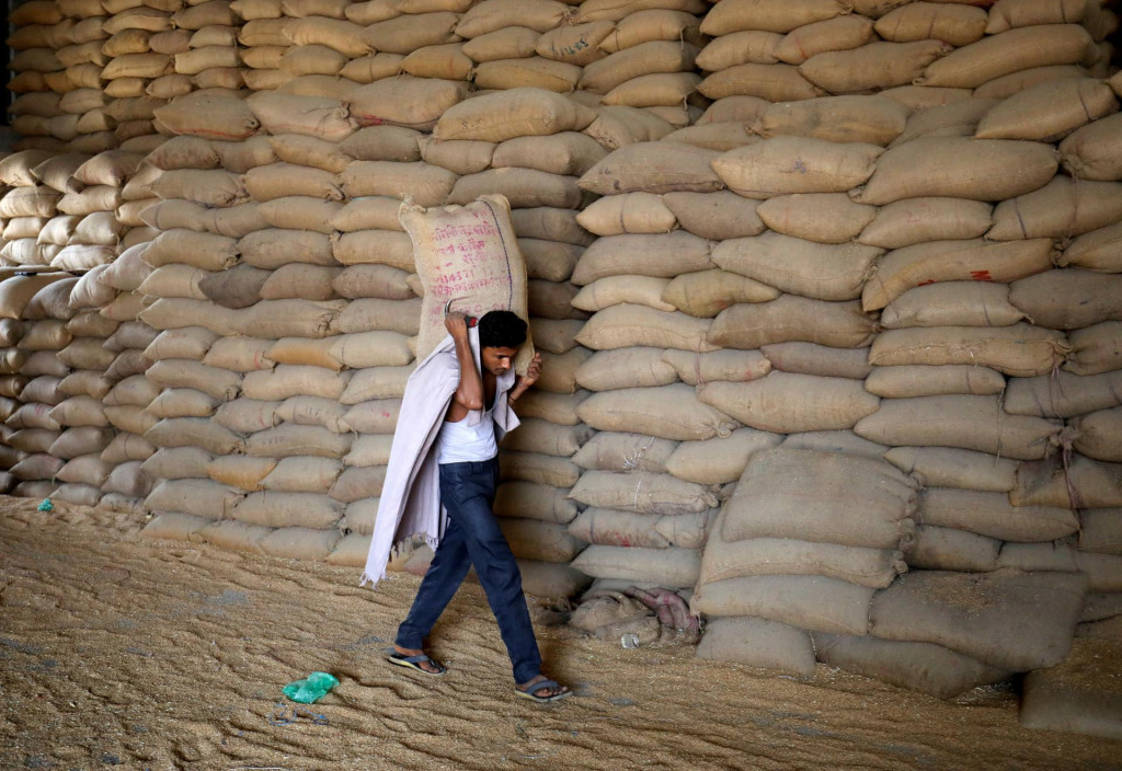 Robotník nesie vrece pšenice na preosievanie v mlyne na obilie k ostatným do skladu obilnín. FOTO: Reuters