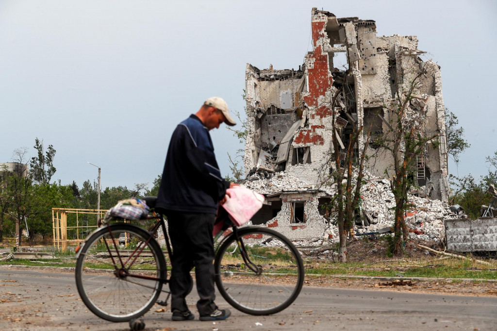 Muž drží bicykel, keď stojí neďaleko budovy zničenej počas ukrajinsko-ruského konfliktu v meste Rubižne v Luhanskej oblasti. FOTO: Reuters