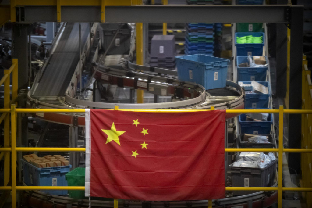 Čínska vlajka visí neďaleko linky na automatickú manipuláciu s balíkmi v sklade pre čínskeho internetového predajcu JD.com v Pekingu. FOTO: TASR/AP

