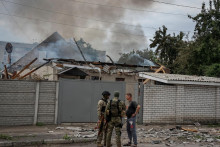 Policajti v Lysyčansku hovoria s miestnym obyvateľom počas toho, ako jeho dom po ruskom ostreľovaní horí. FOTO: REUTERS